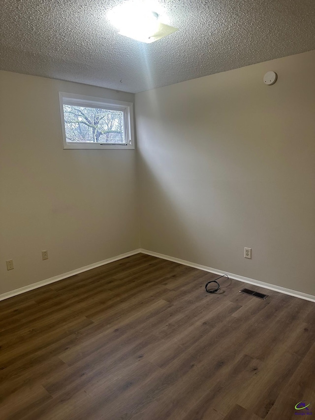 empty room featuring dark hardwood / wood-style floors and a textured ceiling