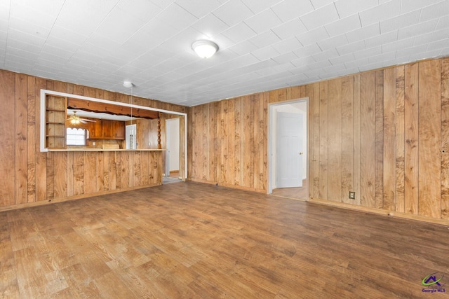 unfurnished living room featuring wood-type flooring and wood walls