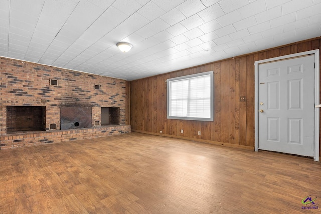 unfurnished living room with wood-type flooring and wooden walls