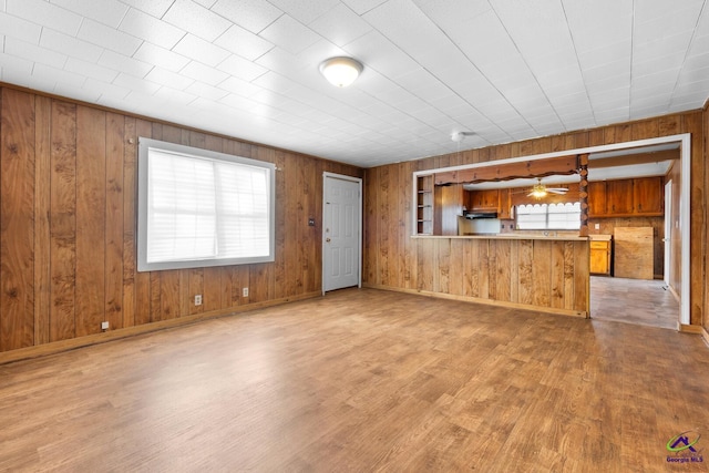 unfurnished living room featuring plenty of natural light, wood-type flooring, and wood walls