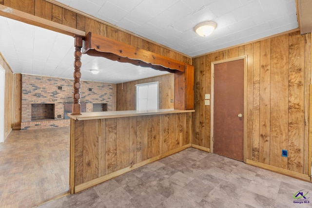 kitchen with a brick fireplace, wooden walls, and kitchen peninsula