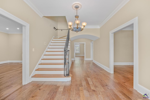 stairway with crown molding, an inviting chandelier, and hardwood / wood-style flooring