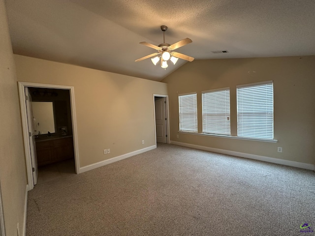 carpeted spare room with a textured ceiling, vaulted ceiling, and ceiling fan