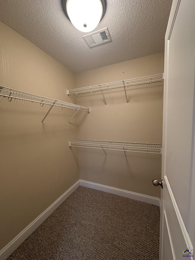 walk in closet featuring dark carpet