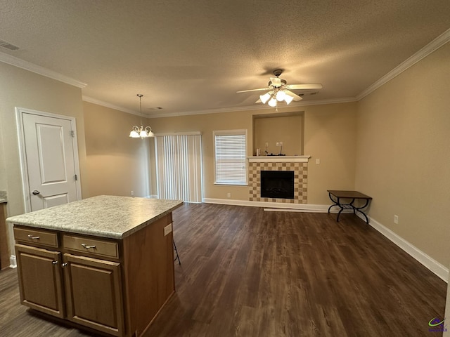 kitchen with ornamental molding, dark hardwood / wood-style floors, a kitchen island, pendant lighting, and a fireplace