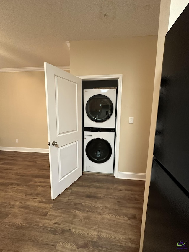 laundry area featuring crown molding, stacked washer and clothes dryer, a textured ceiling, and dark hardwood / wood-style flooring