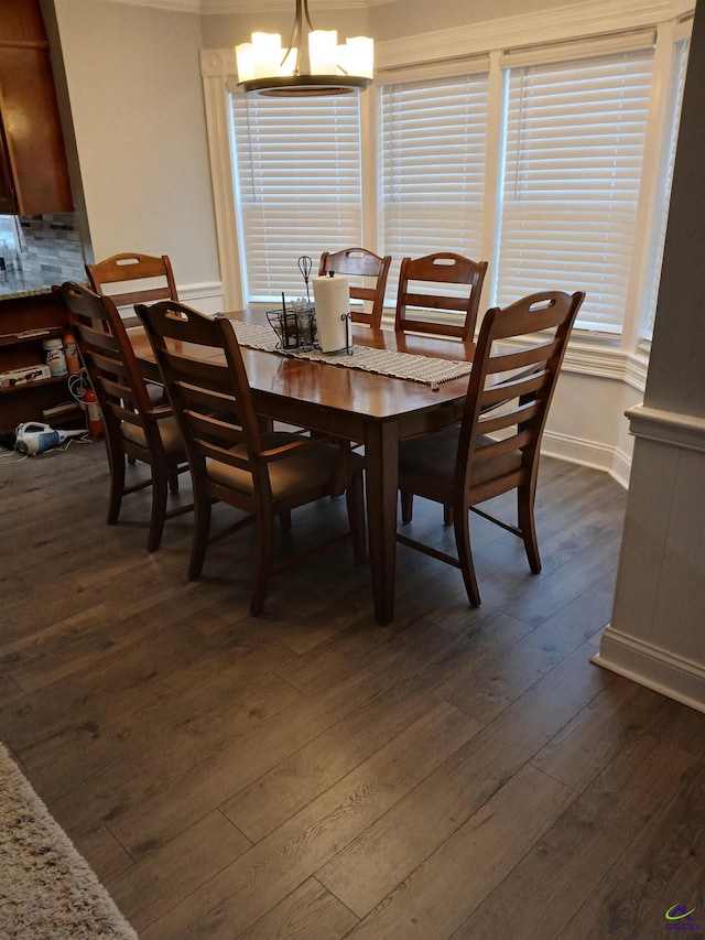 dining space with dark wood-type flooring and an inviting chandelier