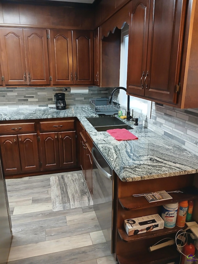 kitchen with sink, light hardwood / wood-style flooring, dishwasher, light stone counters, and tasteful backsplash