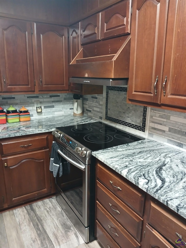 kitchen featuring tasteful backsplash, stainless steel electric range oven, and light stone countertops