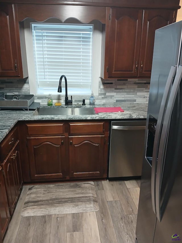 kitchen with light stone counters, sink, dark brown cabinetry, and appliances with stainless steel finishes