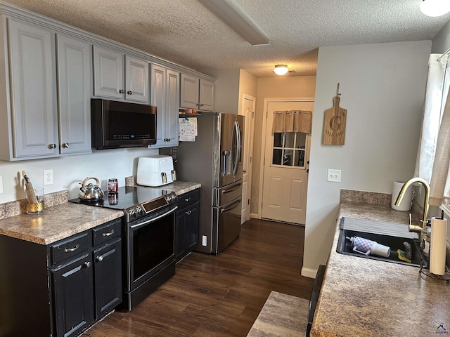 kitchen with stainless steel appliances, sink, dark wood-type flooring, and a textured ceiling