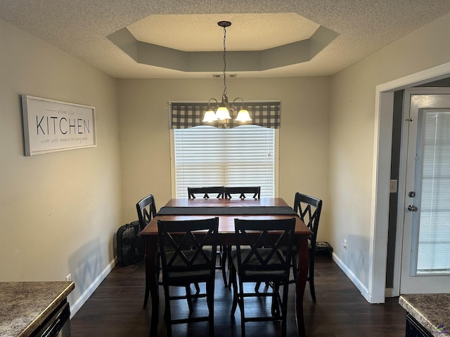 dining room featuring dark hardwood / wood-style floors, a tray ceiling, a wealth of natural light, and a notable chandelier