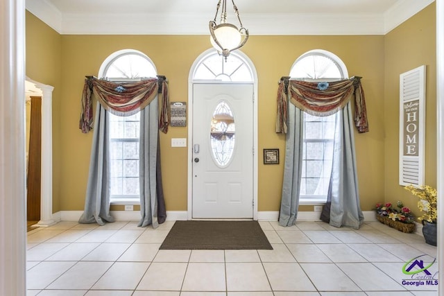 tiled entrance foyer with crown molding and decorative columns