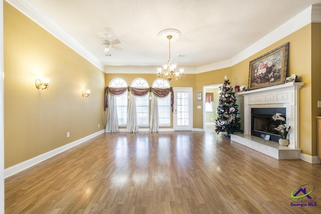 unfurnished living room with wood-type flooring, ornamental molding, and ceiling fan with notable chandelier