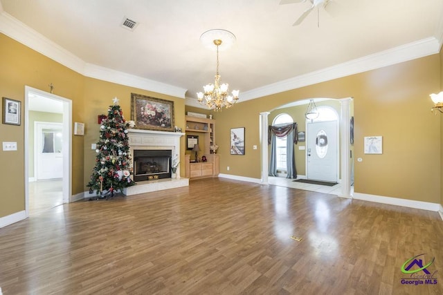 unfurnished living room with crown molding, ceiling fan with notable chandelier, and hardwood / wood-style floors