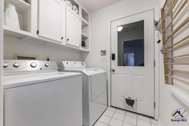 clothes washing area with washer and dryer, light tile patterned floors, and cabinets