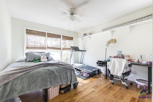 bedroom with ceiling fan, hardwood / wood-style flooring, and a textured ceiling