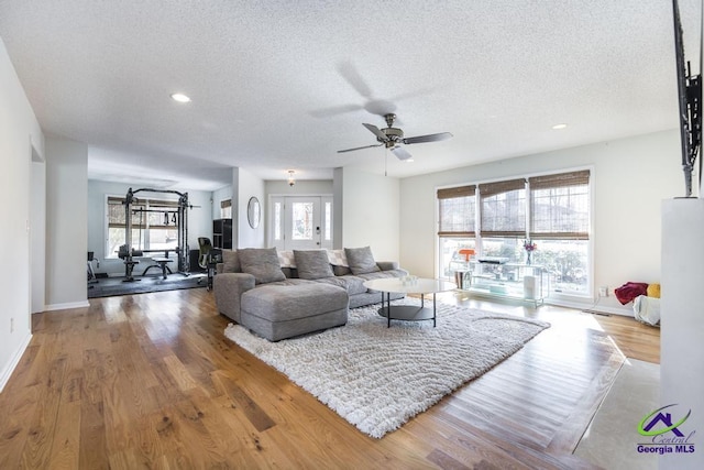 living room featuring hardwood / wood-style flooring, ceiling fan, a wealth of natural light, and a textured ceiling