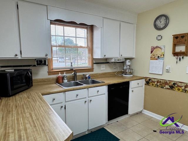 kitchen featuring sink, light tile patterned floors, black appliances, and white cabinets