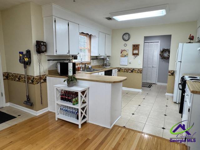 kitchen featuring sink, white cabinetry, light hardwood / wood-style flooring, kitchen peninsula, and black range with electric cooktop