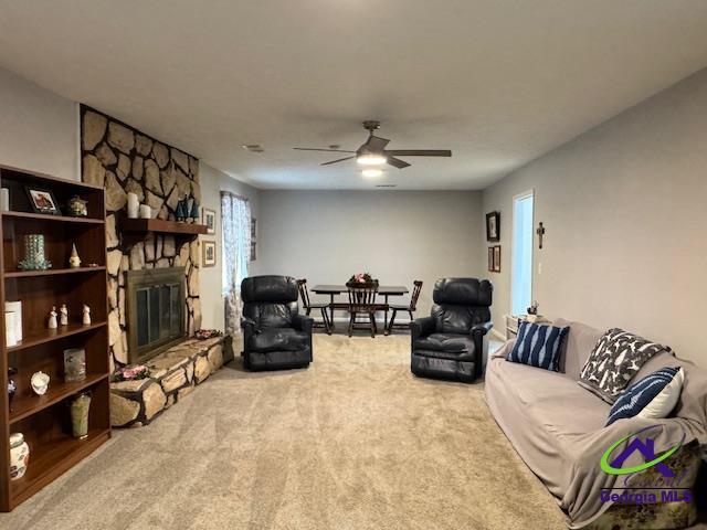 carpeted living room featuring ceiling fan and a fireplace