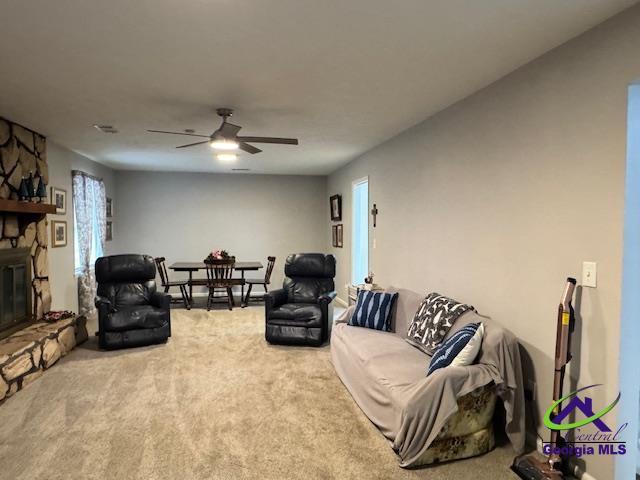 living room with ceiling fan, carpet floors, and a fireplace