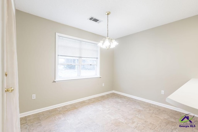 unfurnished room featuring a notable chandelier