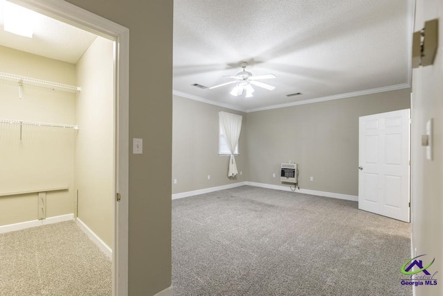 carpeted empty room featuring crown molding, heating unit, a textured ceiling, and ceiling fan