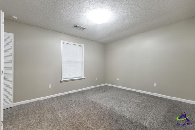 spare room featuring a textured ceiling and carpet flooring