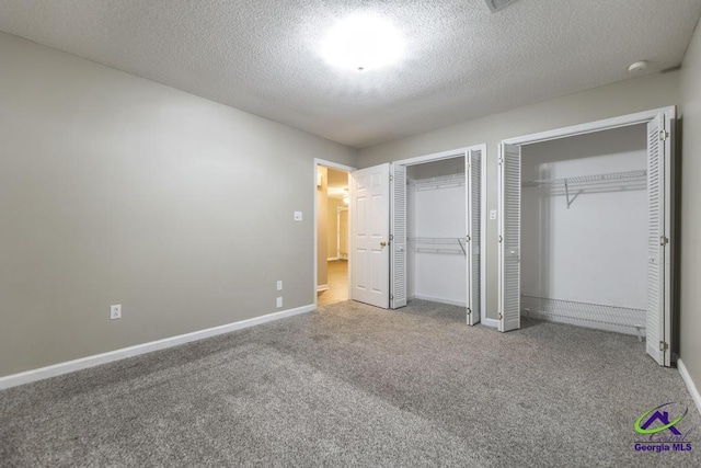 unfurnished bedroom featuring multiple closets, carpet floors, and a textured ceiling