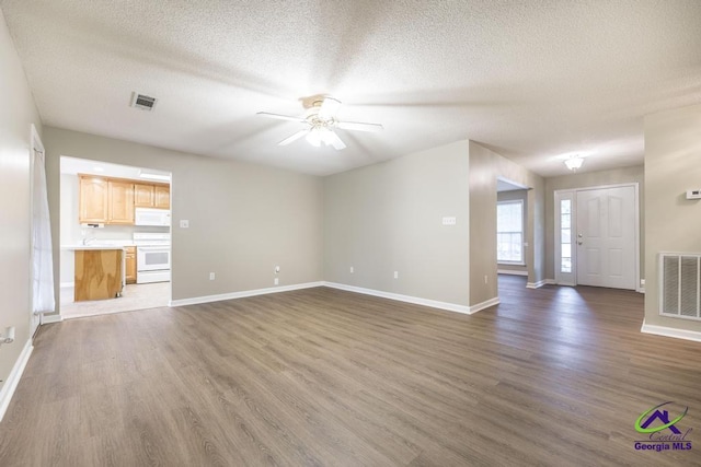 unfurnished living room with ceiling fan, dark hardwood / wood-style floors, and a textured ceiling