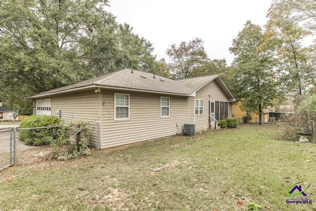 view of side of property featuring central AC, a garage, and a lawn