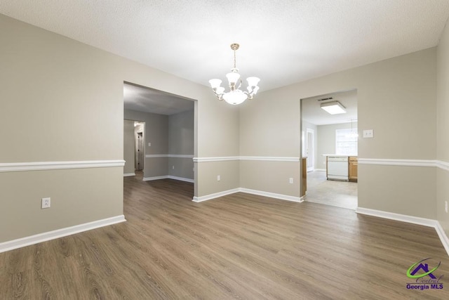 spare room with wood-type flooring, a textured ceiling, and a notable chandelier