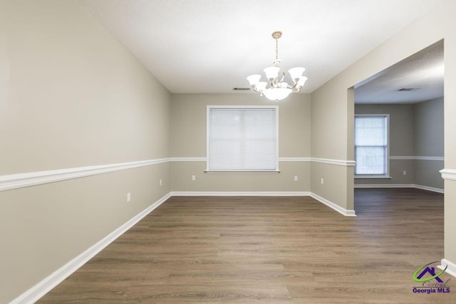 unfurnished room featuring wood-type flooring and a chandelier