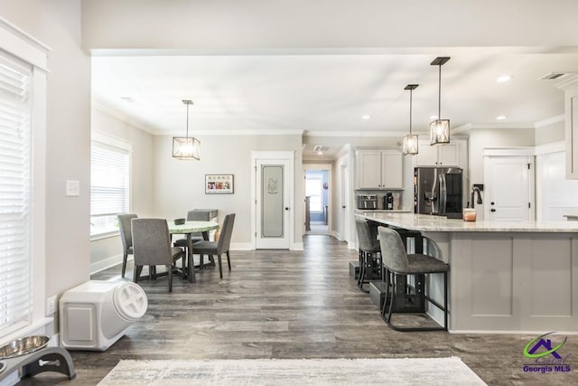 kitchen featuring pendant lighting, light stone countertops, stainless steel fridge, and a kitchen breakfast bar