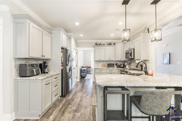 kitchen featuring sink, appliances with stainless steel finishes, white cabinetry, decorative light fixtures, and kitchen peninsula