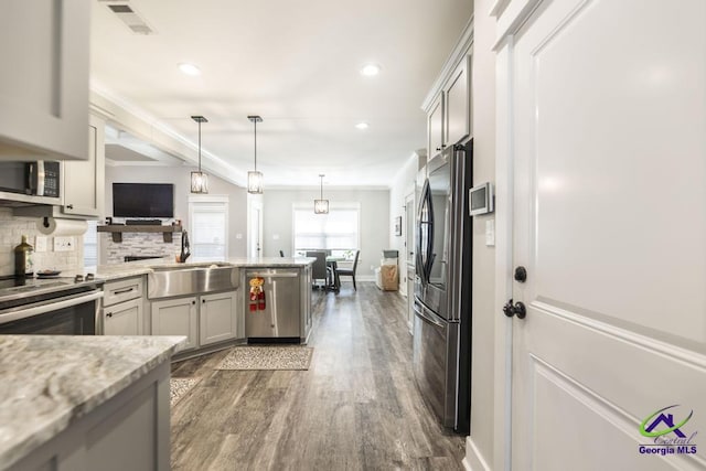 kitchen with appliances with stainless steel finishes, sink, decorative backsplash, hanging light fixtures, and light stone countertops