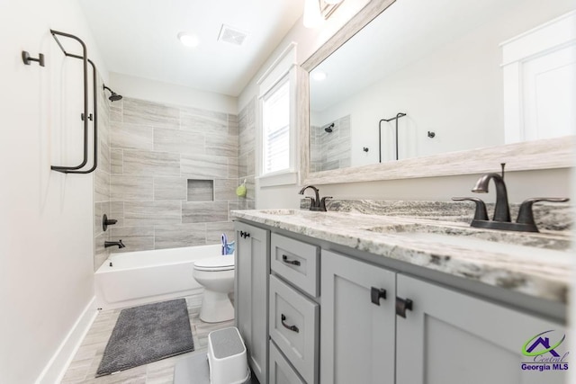 full bathroom featuring tiled shower / bath combo, vanity, and toilet