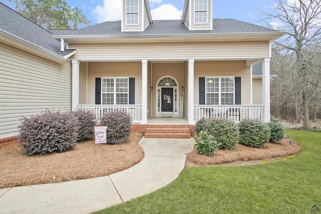 entrance to property with a lawn and a porch