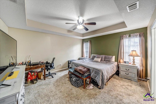 carpeted bedroom with a raised ceiling, ceiling fan, and a textured ceiling