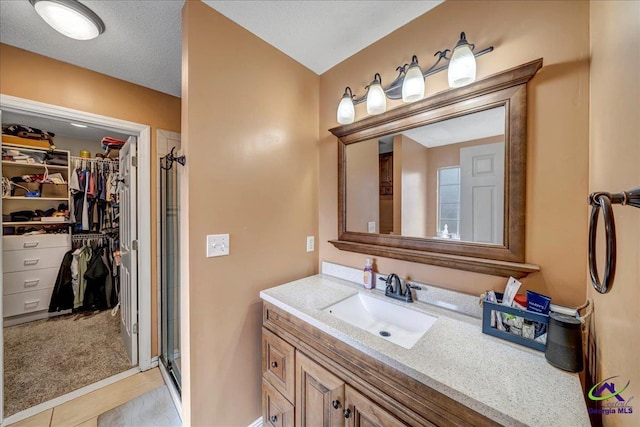 bathroom featuring vanity, an enclosed shower, and a textured ceiling