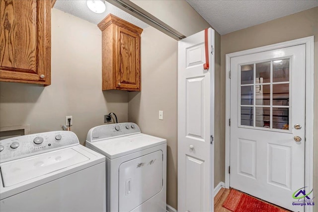 laundry room featuring a textured ceiling, cabinets, washing machine and clothes dryer, and light wood-type flooring