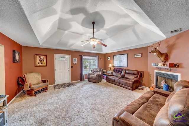 living room with a raised ceiling, carpet floors, and a textured ceiling