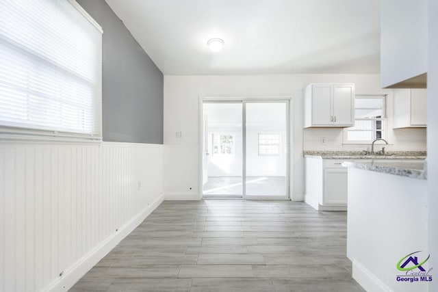 kitchen with white cabinetry, decorative backsplash, and light wood-type flooring