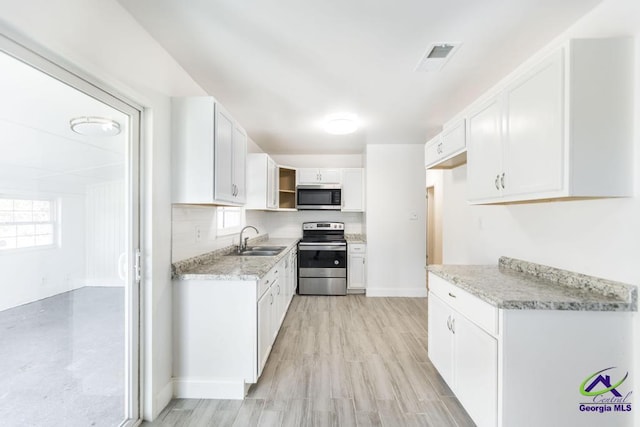 kitchen featuring light stone countertops, white cabinetry, appliances with stainless steel finishes, and sink