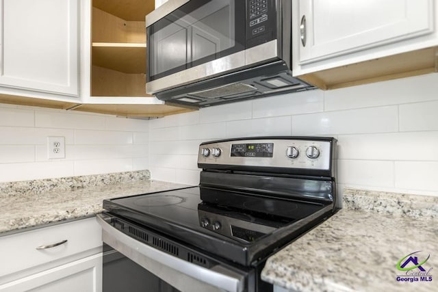 kitchen featuring white cabinetry, light stone counters, tasteful backsplash, and appliances with stainless steel finishes