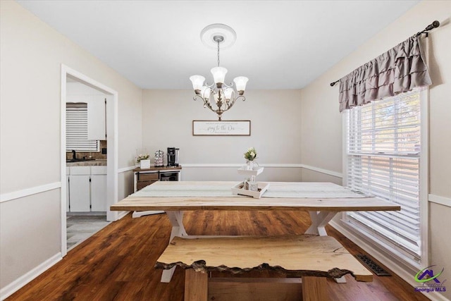 dining space with an inviting chandelier, sink, and light hardwood / wood-style flooring