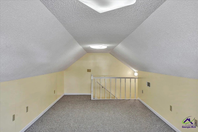 bonus room with carpet flooring, vaulted ceiling, and a textured ceiling