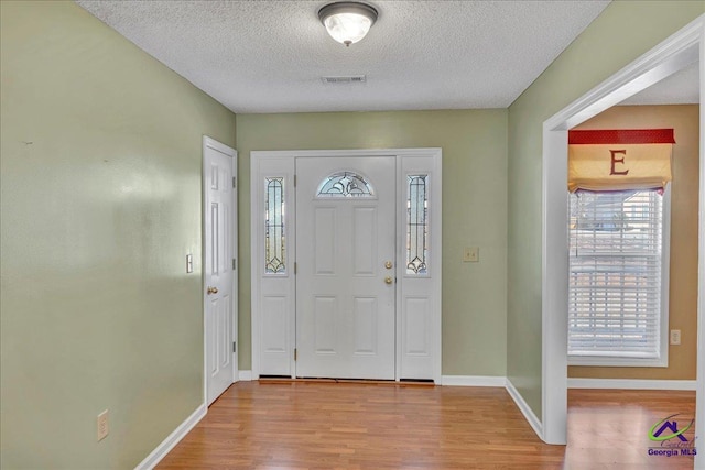 entryway with a textured ceiling and light hardwood / wood-style floors