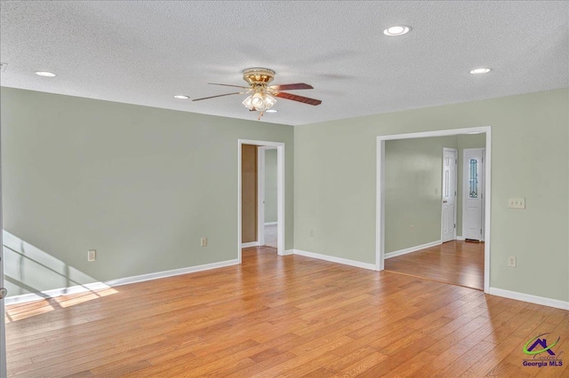 spare room featuring a textured ceiling, ceiling fan, and light wood-type flooring